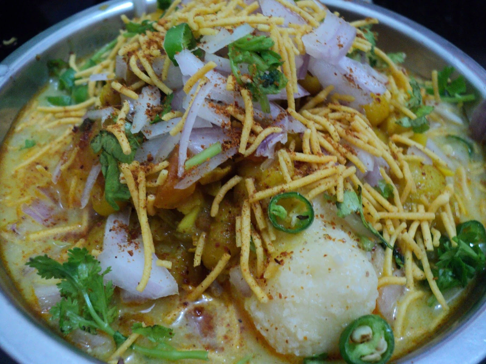 A plate of Dahi Bara Aloo Dum showcasing the tangy yogurt sauce with lentil dumplings and spicy potato curry.