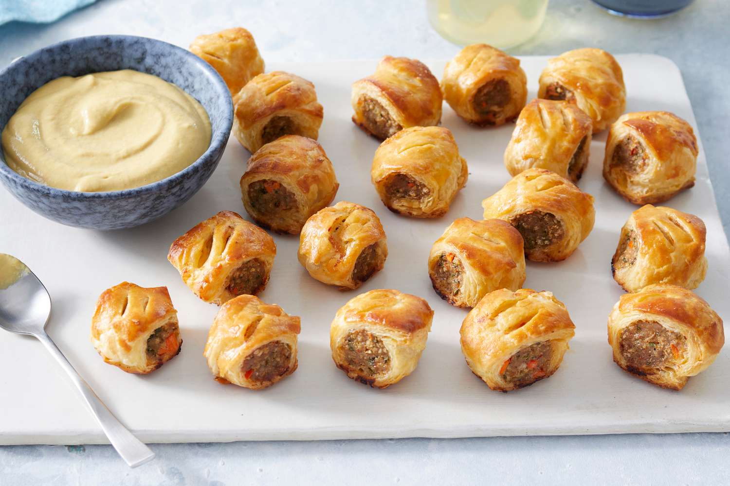 A delicious sausage roll with golden, flaky pastry filled with seasoned sausage meat, served on a wooden board.
