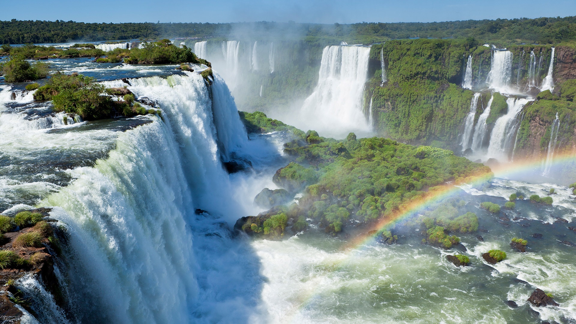 Tourists enjoying a boat ride at the base of Iguazu Falls, experiencing the powerful mist and rainbows.