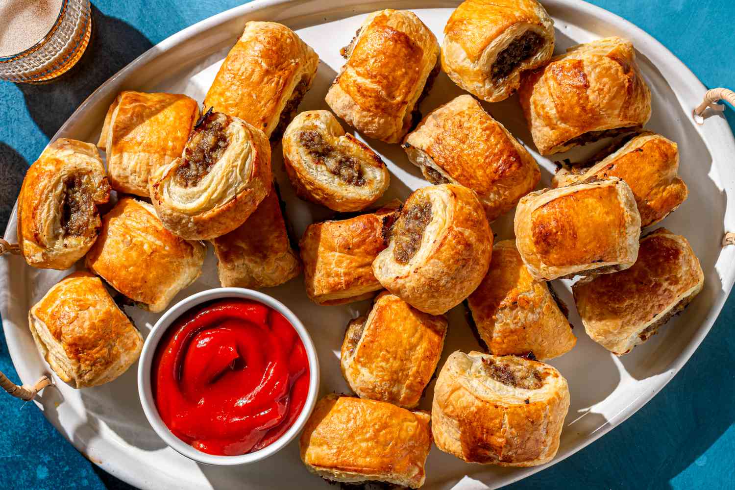 An assortment of sausage rolls, including classic, cheese and herb, and spicy variations, displayed on a rustic table.