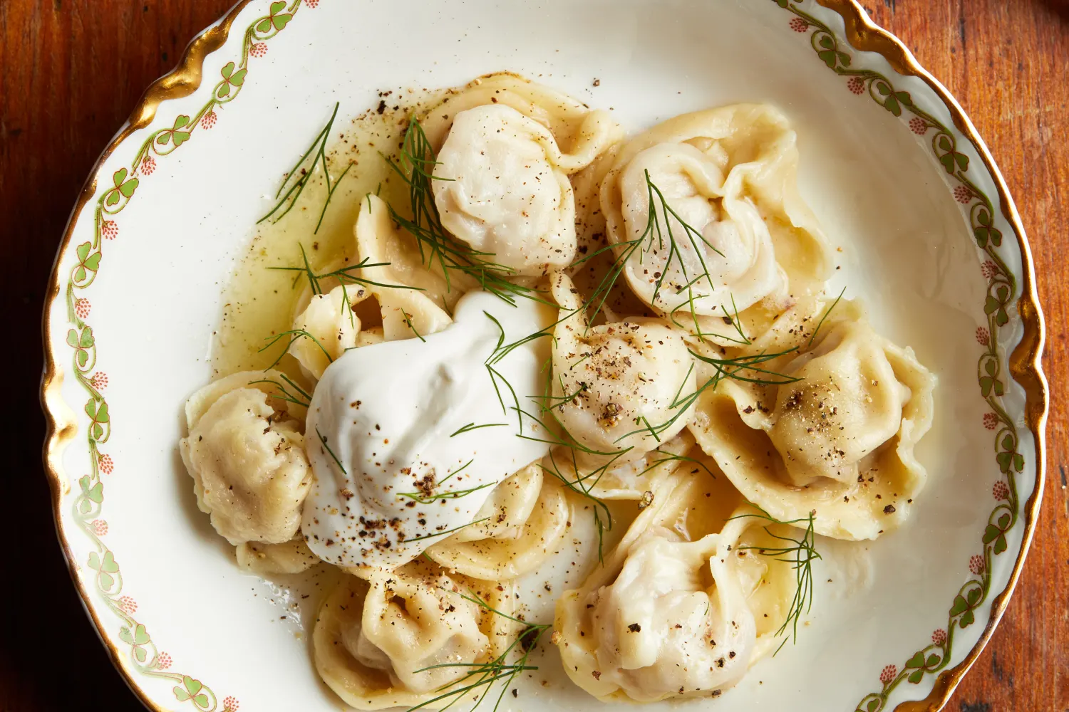 Boiled pelmeni served with melted butter and herbs 