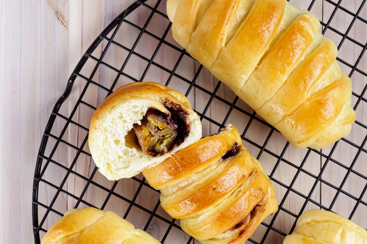 Potongan roti pisang panggang yang lembut dan harum, disajikan hangat dengan topping irisan pisang dan kacang